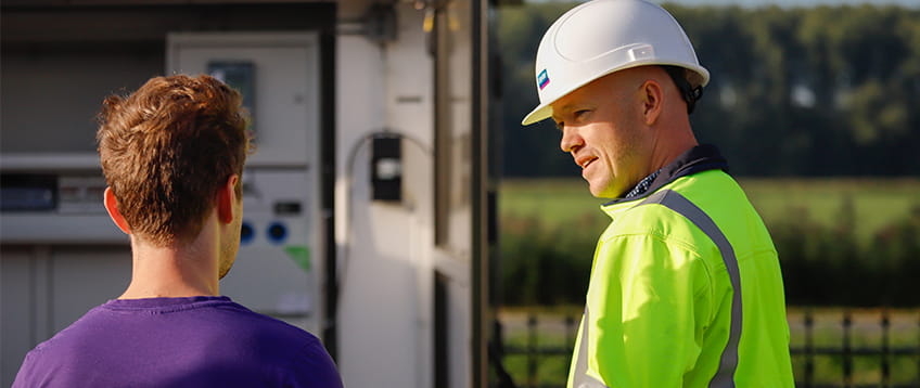 twee mannen praten bij een elektriciteitshuisje